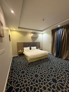 a bedroom with a bed and a blue carpet at ليالي رهيف للشقق المخدومه in Abha