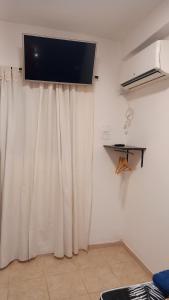 un téléviseur à écran plat sur un mur avec un rideau dans l'établissement Norita Alquiler Temporal - Departamento, à La Rioja