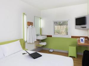a bedroom with a bed with a laptop on it at ibis Budget - Melbourne Airport in Melbourne