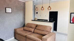 a brown couch in a living room with pendant lights at Apartamento Aconchegante Perto da Dutra in Taubaté
