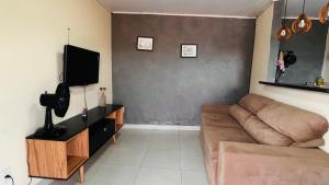 a living room with a couch and a flat screen tv at Apartamento Aconchegante Perto da Dutra in Taubaté