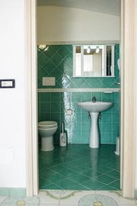 a green tiled bathroom with a sink and a toilet at Hotel Regina del Mare in Ischia +37 photos