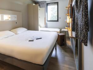 a hotel room with a large bed and a window at ibis budget Rennes Rte Lorient in Rennes +71 photos