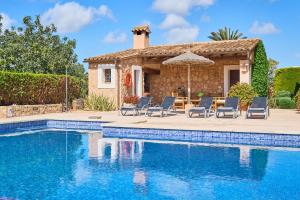 a house with a swimming pool with chairs and an umbrella at Finca Hort Can Veritat in Cala Ferrera