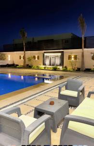 a swimming pool with chairs and a table and a building at Reef Golden Resort شاليه الريف الذهبي in Qaryat ash Shamālī