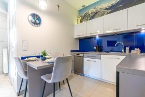 a kitchen with white cabinets and a table and chairs at Aqua Park Residence VIPAPARTAMENTY in Zakopane