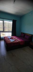 a bedroom with a bed with a red comforter and a window at Ruby bungalow in Ooty +12 photos