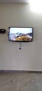 a flat screen tv hanging on a white wall at Ruby bungalow in Ooty