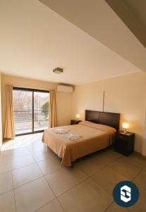 a bedroom with a bed and a large window at Central Suites Hotel in Villa Carlos Paz