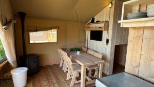 a dining room with a table and chairs in a tiny house at Safari Lodge B in Petten