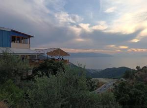 a house on the side of a hill with a road at Hotel Gramozi in Kaninë