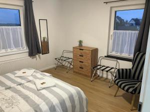 a bedroom with two chairs and a bed and two windows at Borsch urlaub Ferienwohnungen in Geisa +26 photos