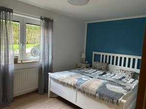 a bedroom with a large bed with a blue wall at Ferienwohnung Dorfliebe in Oettersdorf +5 photos