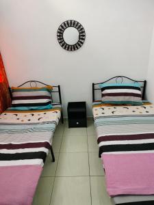 two beds sitting next to each other in a room at Aahana Homestay in Merlimau