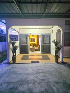 ein Wohnzimmer mit einem Sofa und zwei Pflanzen in der Unterkunft Aahana Homestay in Merlimau + 13 Fotos
