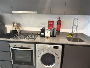 une cuisine avec une cuisinière et une machine à laver dans l'établissement Maison Sahab - Stylish Studio in Tiraz Building, à Charjah 13 autres photos