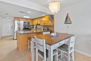 Una cocina con una mesa de madera y sillas blancas. en Win-San A213, en Chicken Island