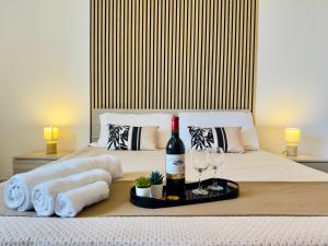 a bed with a bottle of wine and two glasses at Demetra Seafront Apartment - Parking & Pool in Castel Volturno +19 photos