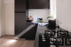 une cuisine avec des armoires noires et un comptoir noir dans l'établissement De Koekoek I Modern en vrijstaand vakantiehuis in het bos, à Nunspeet