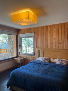 Un dormitorio con una cama azul y una gran ventana. en Huella Blanca, en San Martín de los Andes 47 fotos más