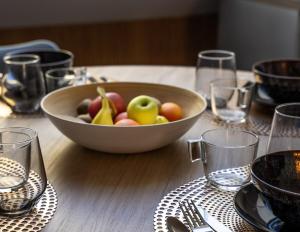 Un bol de fruta en una mesa de madera con vasos. en Le Loft - Place Flore - Besançon, en Besançon