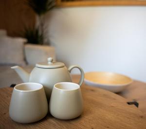 Tres tazas blancas sobre una mesa de madera con una tetera. en Le Loft - Place Flore - Besançon, en Besançon