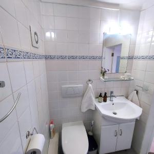 a white bathroom with a toilet and a sink at Seaside haven in Simonʼs Town