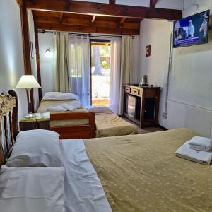a hotel room with two beds and a television at Hostal La Merced in Villa General Belgrano +70 photos