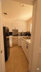Una cocina con gabinetes blancos y un refrigerador negro. en La Casa Hotel, en Fort Lauderdale
