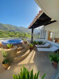 a patio with a pool and chairs and mountains at PENTHOUSE EN PLAYA EL AGUA in Los Cerritos