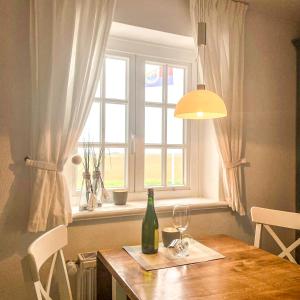 a table with a bottle of wine and a window at Warfthüs, App 7 in Rantum +7 photos