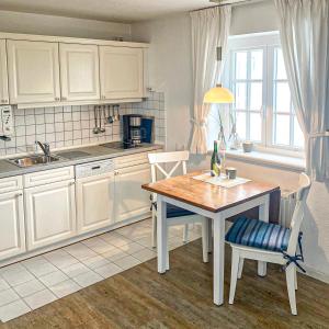 a kitchen with white cabinets and a table and chairs at Warfthüs, App 7 in Rantum