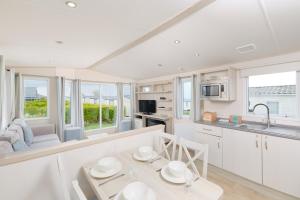 a kitchen with white cabinets and a table and chairs at Wooda Farm Holidays in Bude