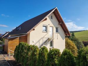 una casa con un tetto nero e alcuni cespugli di Ferienwohnung am Bach a Unterkirnach
