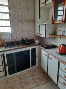 a small kitchen with white cabinets and a sink at Vila Hostel Santos in Santos