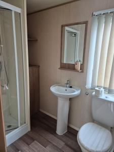 a bathroom with a sink and a toilet and a mirror at Caravan by the Sea 641 in Kinmel Bay