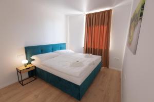 a bedroom with a bed with a blue headboard and a window at Quantara Resort Domaša in Holčíkovce