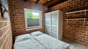 Boerenslag 44 في سينت مارتنسي: غرفة من الطوب مع سرير ونافذة