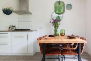 une cuisine avec une table, des chaises et un vase de fleurs dans l'établissement Grove Den I Heerlijk vakantiehuis met bosrijke tuin, à Nunspeet 16 autres photos