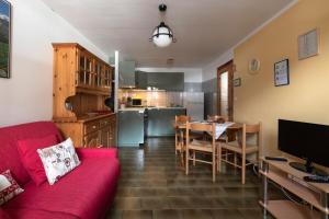 a living room with a red couch and a kitchen at Case Gran Paradiso Rhemes Notre Dame Piazza in Rhêmes-Notre-Dame