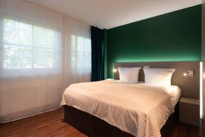 um quarto com uma cama com uma parede verde em Loft Apartments - nähe Hautbahnhof - urbane Umgebung - Küche em Nuremberga