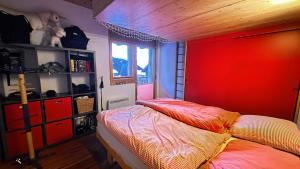 a bedroom with a bed and a red wall at Mon Rêve Bijou in Bettmeralp