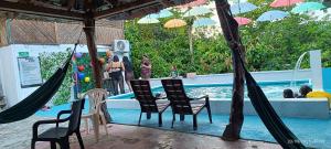a group of chairs and a swimming pool with a pool at Las Cascadas Hostel in Buritaca