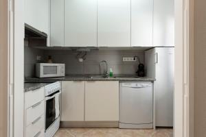 a kitchen with white cabinets and a white refrigerator at NUZZA - Vilamoura Marina with BBQ in Vilamoura