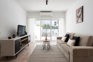 a living room with a couch and a tv at NUZZA - Vilamoura Marina with BBQ in Vilamoura