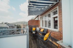 a balcony with yellow pillows and chairs on a building at Waterfront River Side Roof Top Apartment - Terrace with city view in Prague