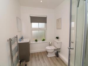 a bathroom with a toilet and a sink and a window at Four in Peterborough
