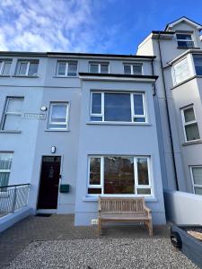 a white house with a bench in front of it at Harbour Views 3 Bed Townhouse with private off street parking and office in Portstewart