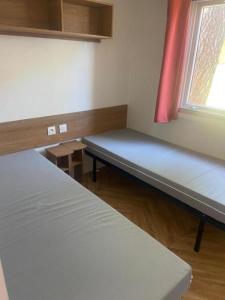 a room with two beds and a window at Chez Maya 2 chambres dont suite parentale et 2 salles de bain dans camping 4 étoiles in Saint-Julien-en-Born +13 photos
