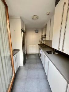 a kitchen with white cabinets and a large window at Casa exclusiva l Chimenea l Wifi l Garaje l Pool in Biescas